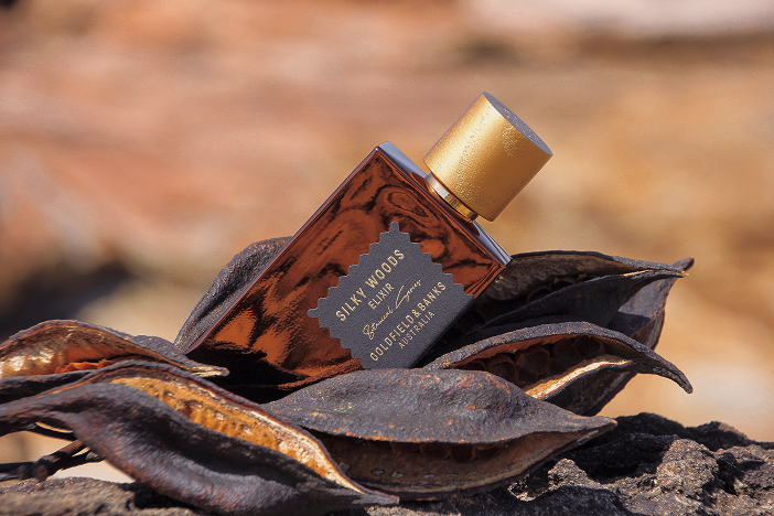 Goldfield & Banks Silky Woods Elixir bottle on dried pods in a warm natural setting.